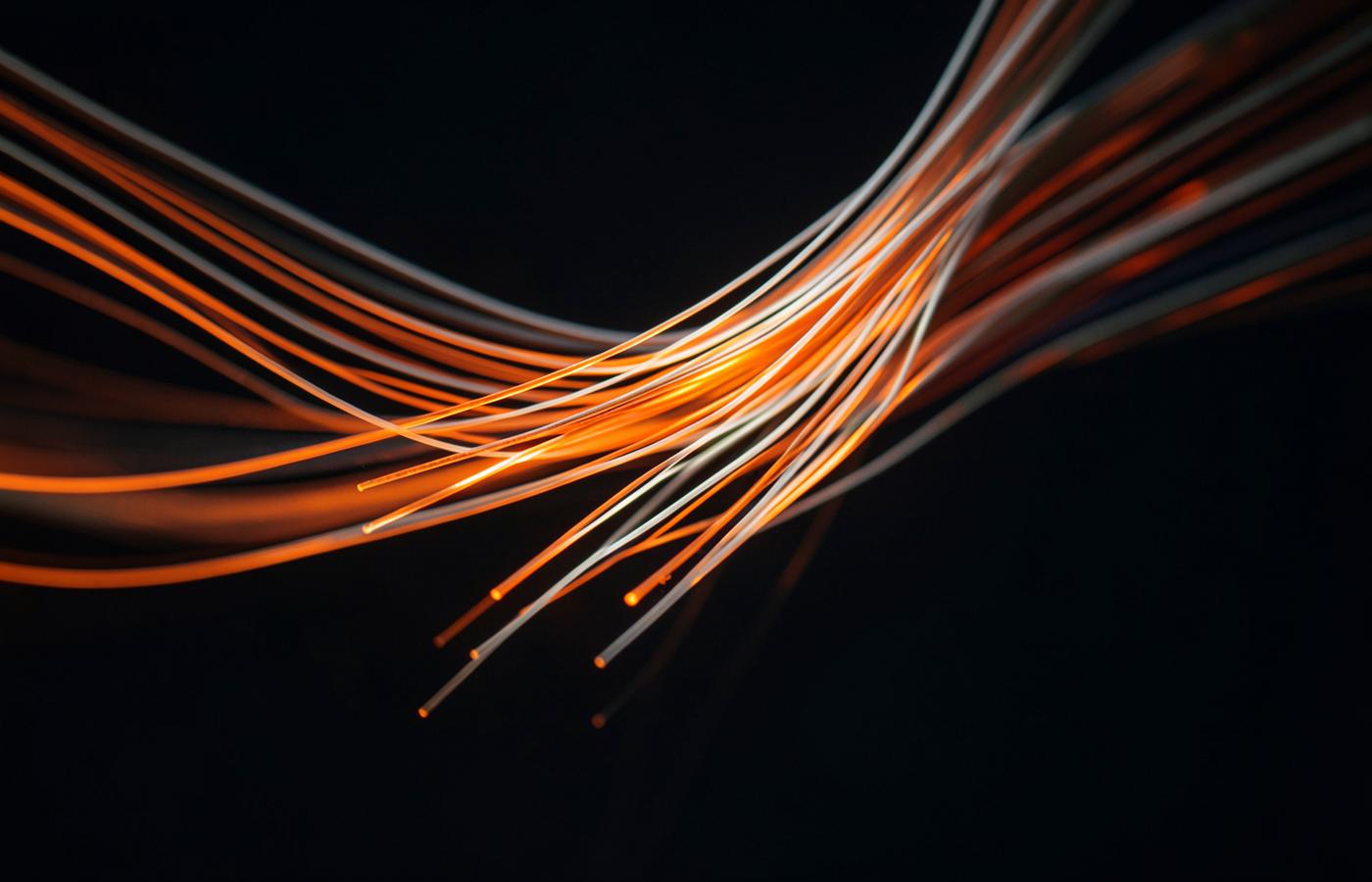 Glowing orange and white fibre-optic strands against a dark background